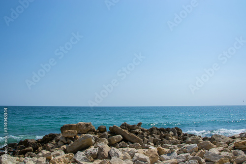 Beautiful wild beach landscape, sunny day, water waves hitting the cliffs, nature summertime scene