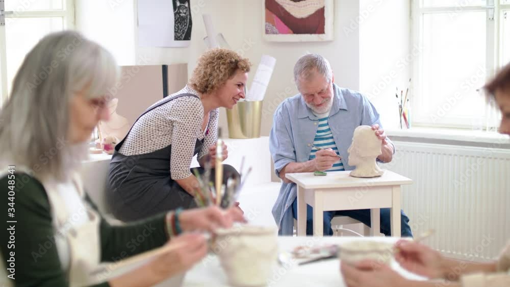 Group of senior people with teacher working with clay on ceramics workshop.