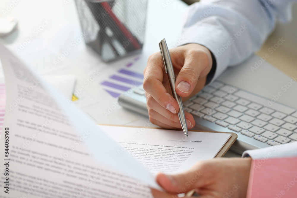 Hand of businessman in suit filling and signing with silver pen partnership agreement form clipped to pad closeup. Management training course some important document team leader ambition concept Hand of businessman in suit filling and signing with silver pen partnership agreement form clipped to pad closeup. Management training course some important document team leader ambition concept