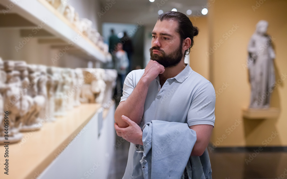 Man looking at stone architectural elements in historical museum hall