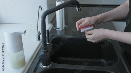 Woman washes hands with soap in the kitchen with brush photo