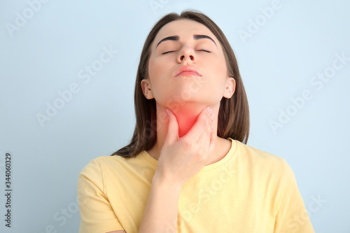 Young woman checking thyroid gland on color background