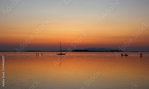 sailing boat and canoe moored on the sea at sunset and headland on the background