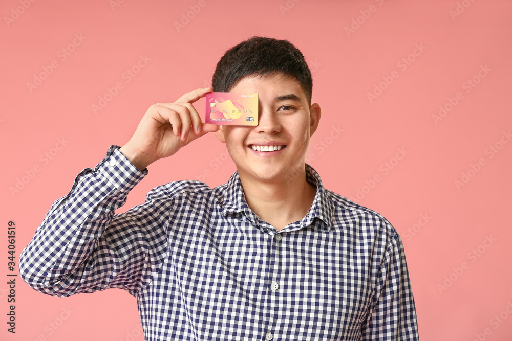 Asian man with credit card on color background Asian man with credit card on color background