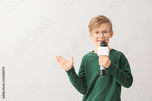 Little journalist with microphone on white background