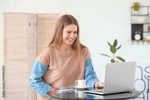 Young woman drinking coffee while working on laptop in cafe