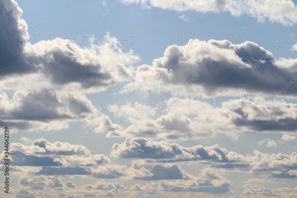 Fototapeta premium Clouds in the blue sky at sunset or dawn backlit by the sun. Place for text and design.