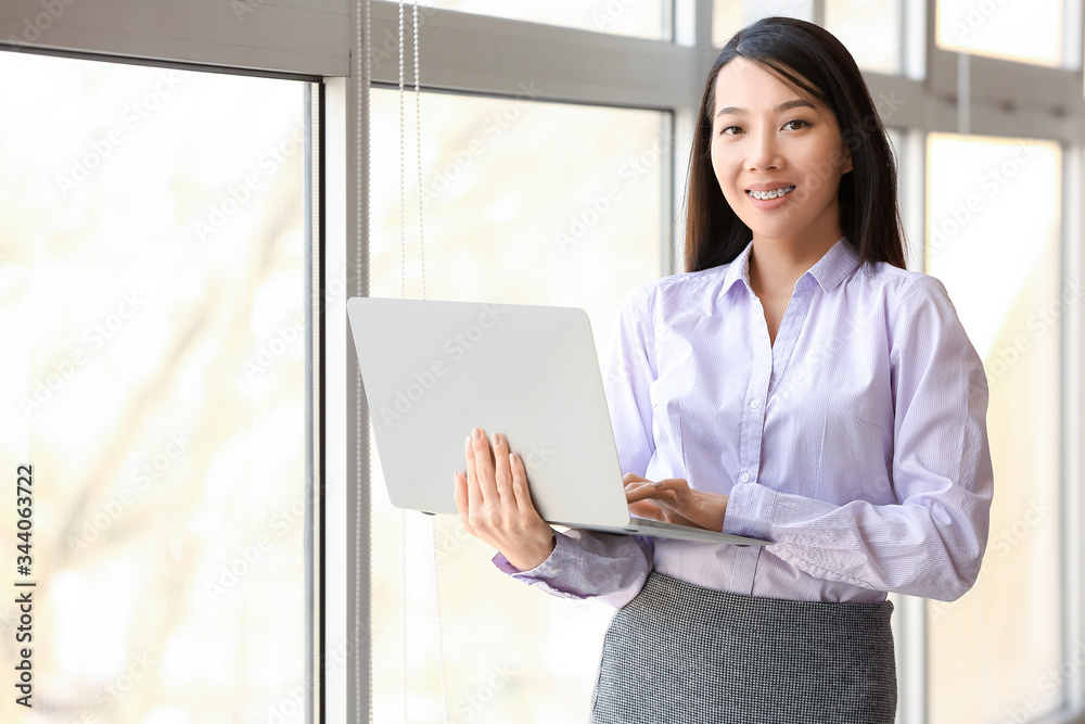 Portrait of young Asian businesswoman with laptop in office Portrait of young Asian businesswoman with laptop in office