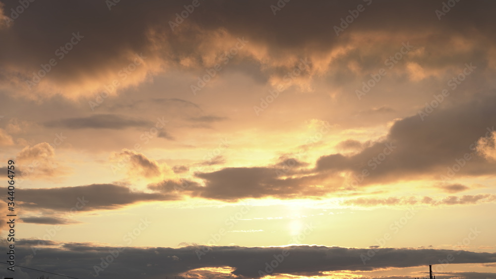 Fototapeta premium Beautiful evening blue sky at sunset with flaming bright light clouds. A warm summer evening at sunset.
