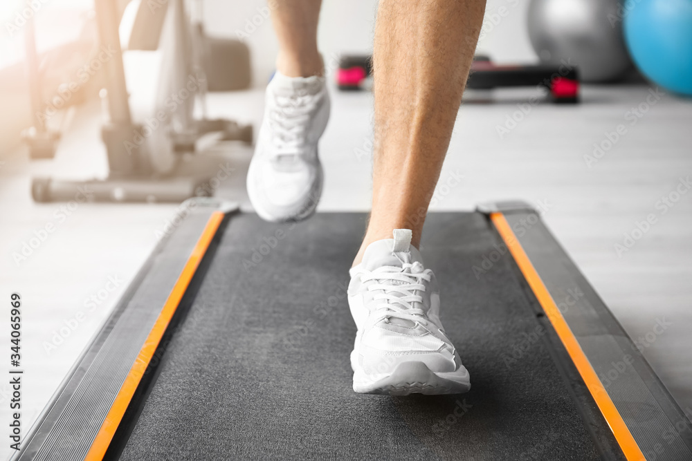 Young man training on treadmill in gym