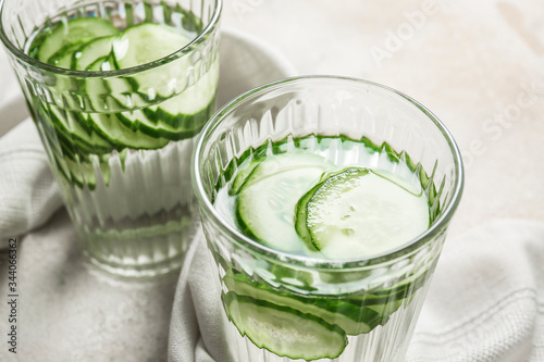 Glasses of infused cucumber water on light background