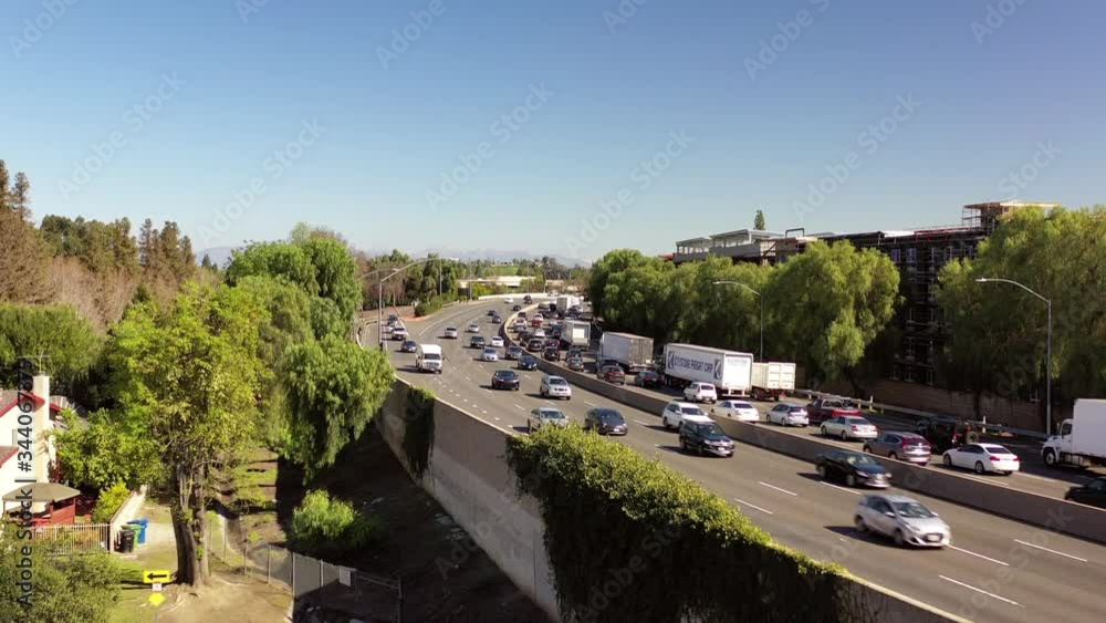 Aerial: Tilt up shot of vehicles moving on elevated road in city against clear sky - Woodland Hills, California