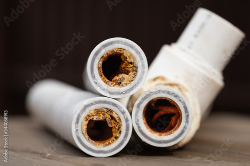 Old broken sludge polypropylene plumbing pipes with red rust and limescale. Corrosion, sludge and hard water concept. Rust broken water pipes