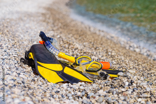 Flippers and snorkeling tube on sea shore