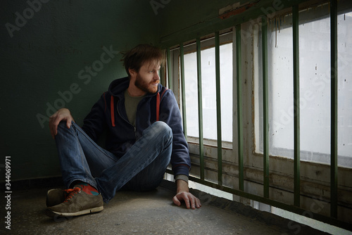depressive male sitting by the window with cage