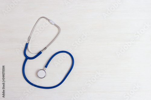 Stethoscope blue colored on white wooden background with copy space. Healthcare and medical concept. World health day. View from above.