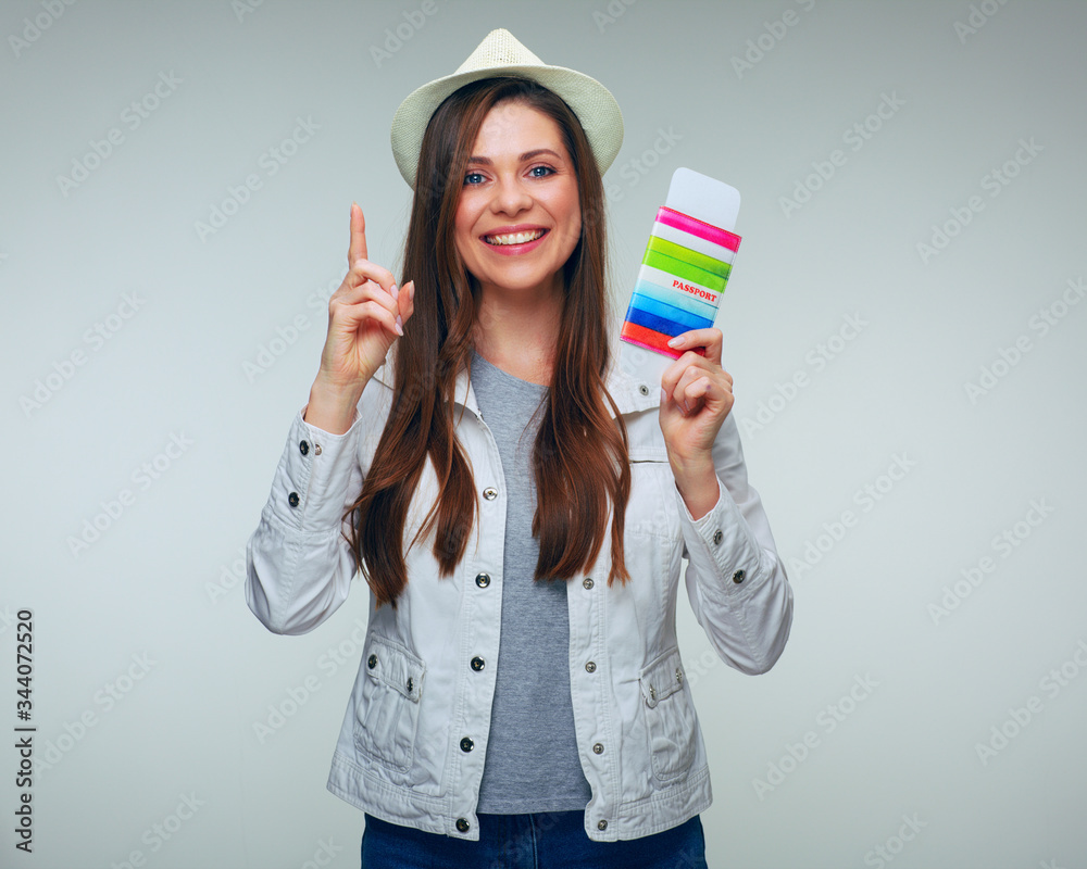 Smiling woman traveler dressed casual holding passport with ticket and pointing finger up Smiling woman traveler dressed casual holding passport with ticket and pointing finger up