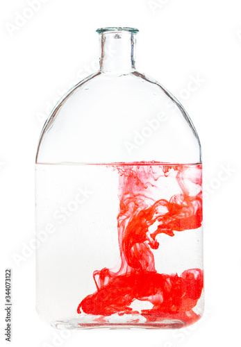 red watercolour dissolves in water in glass flask isolated on white background