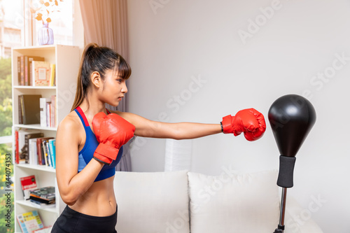 Foto Female woman boxer hitting punching bag in living room at home, practice martial