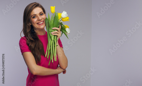 Smiling woman in red dress holding yellow and white tulips.
