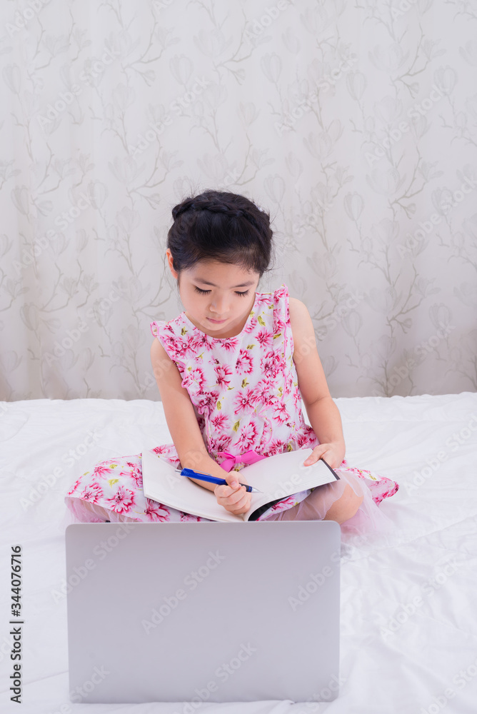 A girl is using a computer in bed to happily study online at home while at home during the period of the outbreak of the covid-19 virus. A girl is using a computer in bed to happily study online at home while at home during the period of the outbreak of the covid-19 virus.