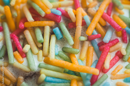 Confectionery topping in the form of sticks of pink, yellow, green and blue, close-up, macro shot.