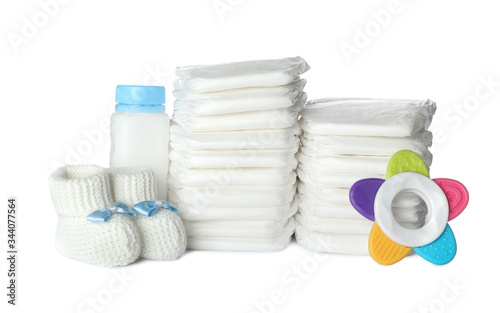 Disposable diapers, child's booties, teether and bottle on white background