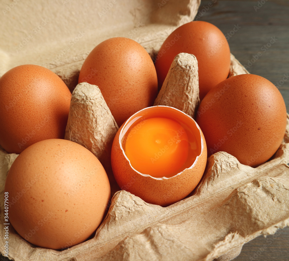 Opened shell fresh organic egg showing egg yolk in the carton box