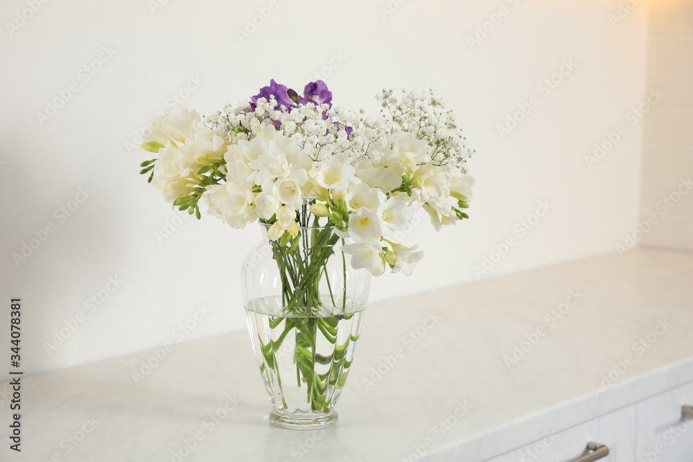 Beautiful bouquet with fresh freesia flowers in vase on cabinet indoors Beautiful bouquet with fresh freesia flowers in vase on cabinet indoors