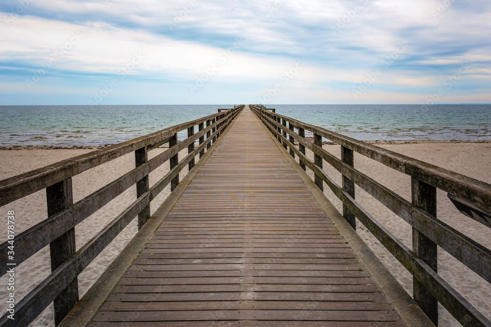 Wooden pier leads straight over the beach and the sea to the horizon, concept for the way forward into an uncertain future, copy space Wooden pier leads straight over the beach and the sea to the horizon, concept for the way forward into an uncertain future, copy space