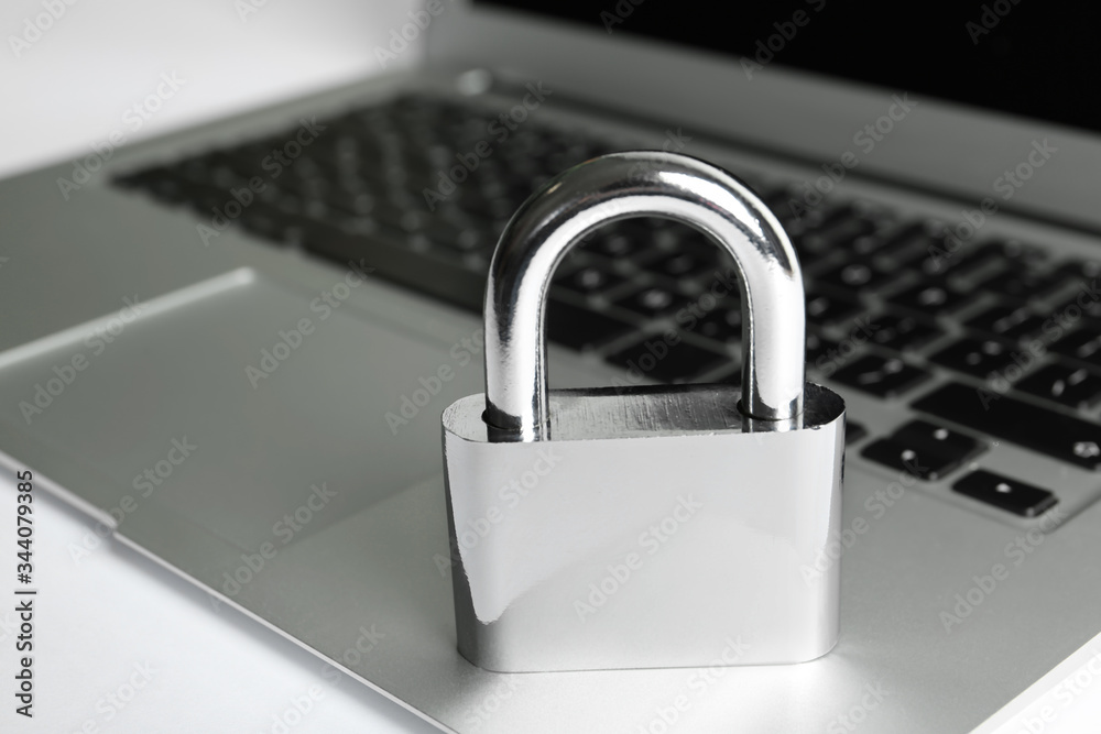 Metal lock and laptop on table, closeup. Protection from cyber attack Metal lock and laptop on table, closeup. Protection from cyber attack