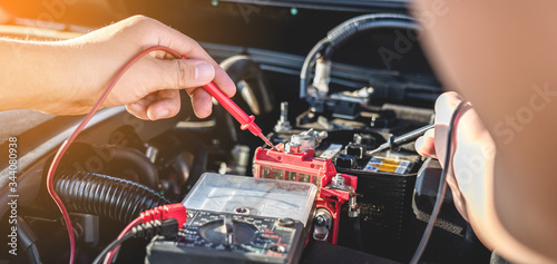 Mechanic repairman checking engine automotive in auto repair service and using digital multimeter testing battery to measure various values and analyze, Service and Maintenance car battery check