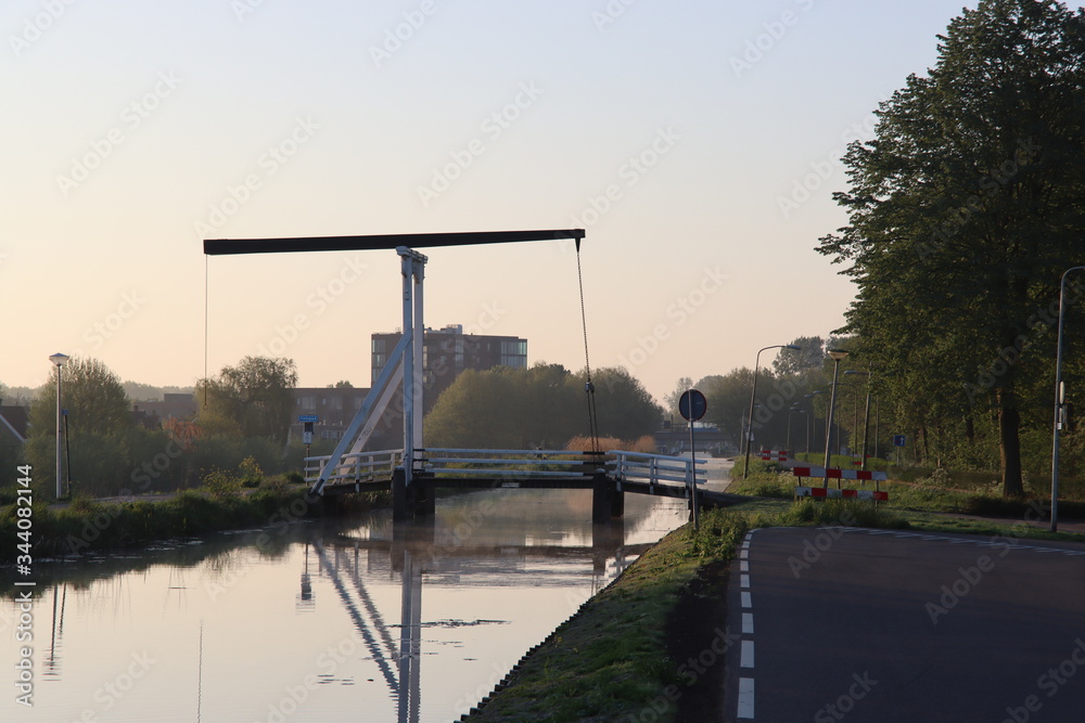 Wooden drawbridge called Witte Brug during sunrise in the town of Nieuwerkerk aan den IJssel over the ring canal of the Zuidplaspolder Nederland Wooden drawbridge called Witte Brug during sunrise in the town of Nieuwerkerk aan den IJssel over the ring canal of the Zuidplaspolder Nederland