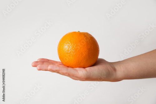 Bright orange fruit placed on flat human palm. Cropped shot, side view, isolated on white. Healthy nutrition or organic food concept