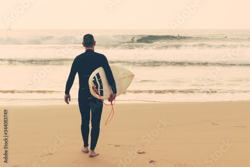 Fotografia Back view of man with surfboard on beach