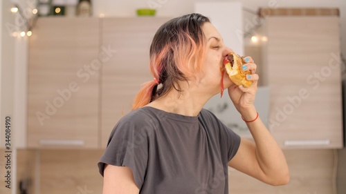 Portrait of caucasian young beautiful woman greedily eagerly eating food during quarantine due to coronavirus. Charming happy hungry woman on diet laugh and biting off big meat pie. Close up.