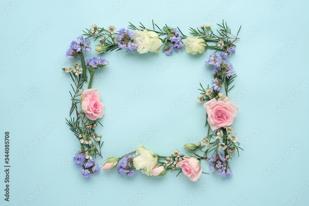 flower frame on blue background, composition of roses, limonium, eustoma, top view, flat lay, copy space