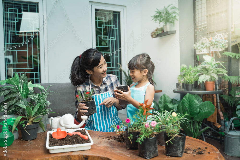 happy kid and mother gardening at home and using smartphone technology to advanced the technique happy kid and mother gardening at home and using smartphone technology to advanced the technique