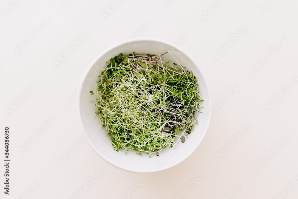 Bowl with organic green sprouts on white table. Bowl with organic green sprouts on white table.