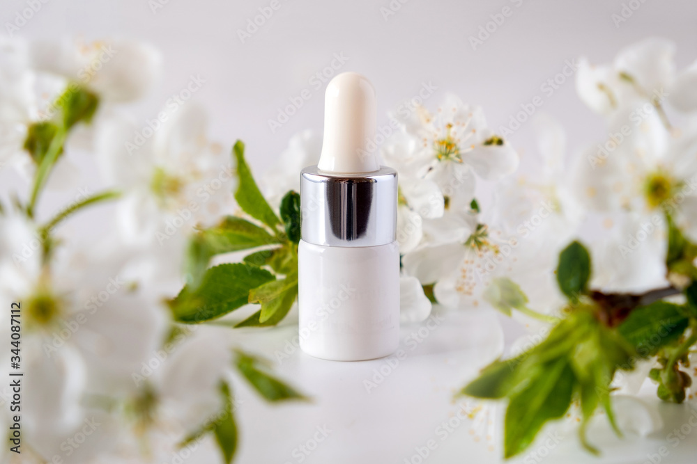 White cosmetic skincare dropper bottle packaging cherry blossoms flowers on white background
