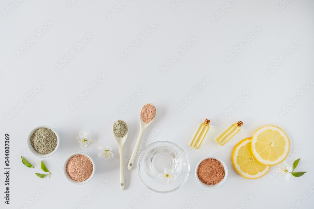 Set of different cosmetic clay mud powders on white background. Ingredients for homemade facial and body mask or scrub and fresh sprig of flowering cherry . Spa and bodycare concept. Set of different cosmetic clay mud powders on white background. Ingredients for homemade facial and body mask or scrub and fresh sprig of flowering cherry . Spa and bodycare concept.