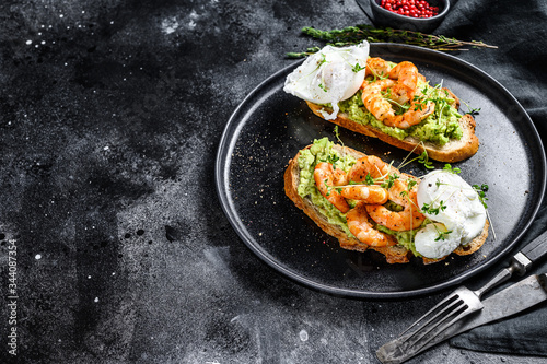 Sandwich topped with fresh prawns, shrimps on avocado with egg. A healthy food, Scandinavian cuisine. Black background. Top view. Copy space