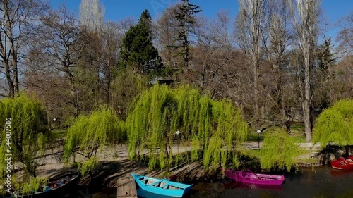 Tranquil water on canal of park with trees and anchored boats on bank under green willows on a spring day in Drilon, Albania photo