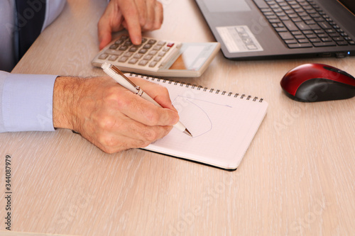 A businessman holds a pen and on schedule calculate data.