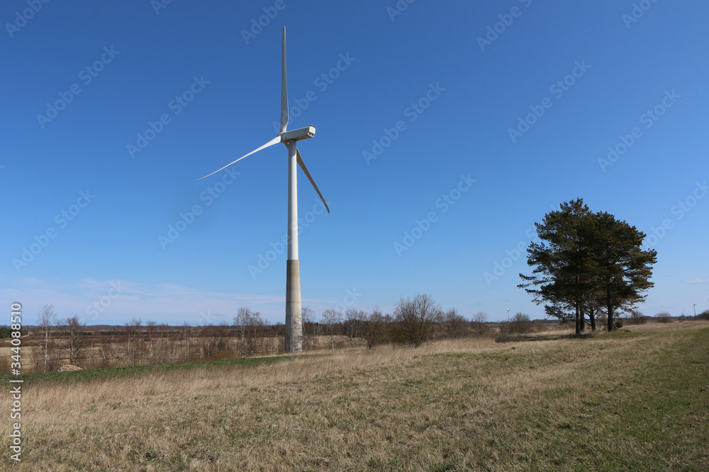 Fototapeta premium A wind turbine rotates against a blue sky.