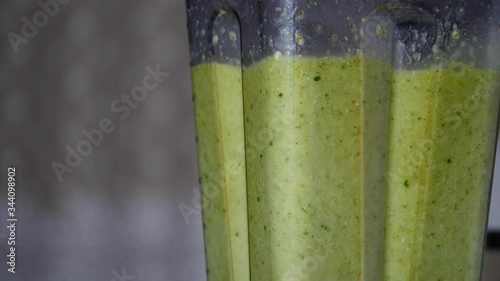 Making healthy shake cocktail. Close up blender jar with fresh green color smoothie fruits vegetables mixture. Blended ingredients spinning