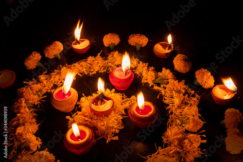 Side view of Rangoli flowers and candles or diyas placed beside them, Diwali lghts at night. Dark background Stock image. photo