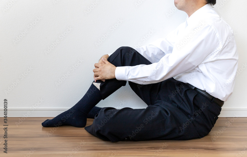 床に座って休んでいるワイシャツを着た男性 床に座って休んでいるワイシャツを着た男性