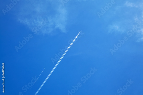 Plane trails in blue sky with white clouds