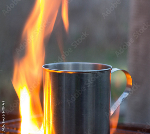 Metal cup with tea warming on fireplace outdoors. dry alcohol brazier Alcohol burner